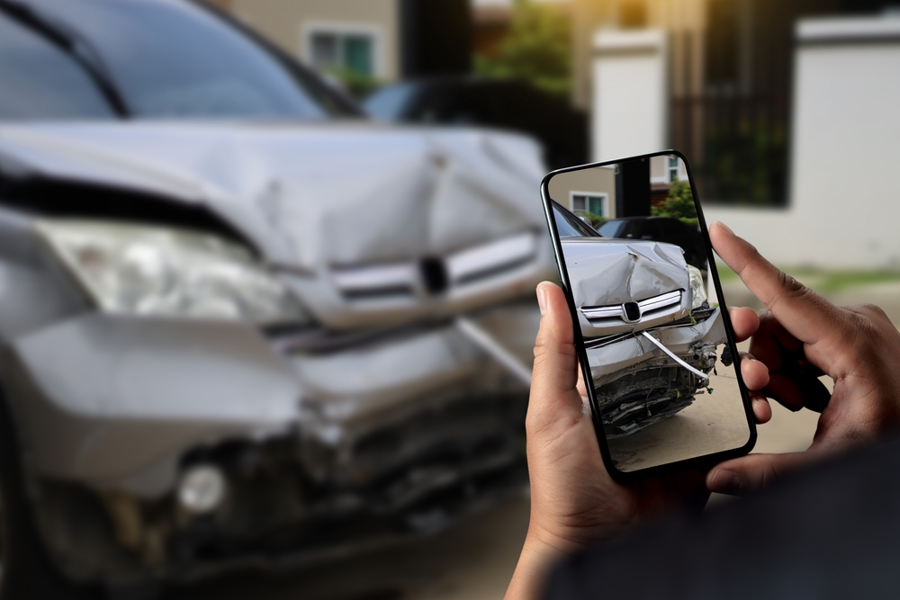 Man taking picture on smart phone of car accident