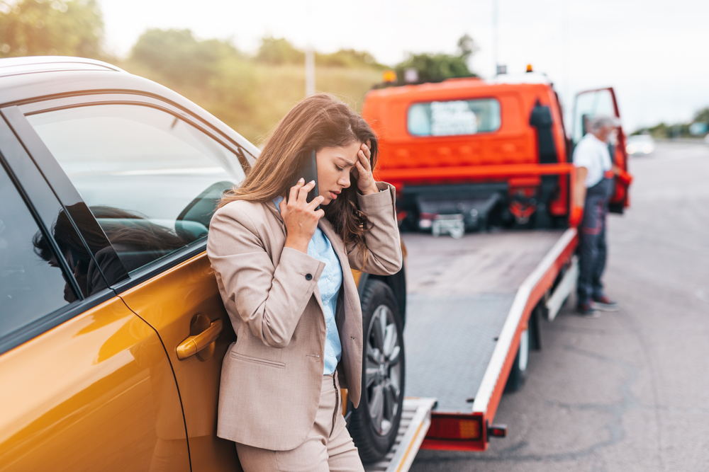 Woman on phone after car accident in Florida with tow truck