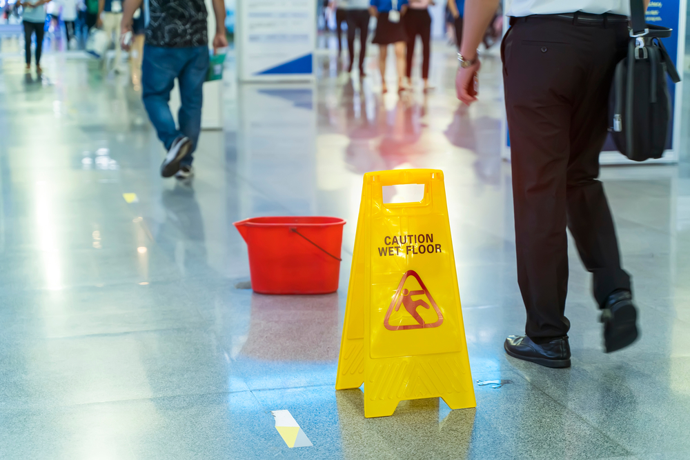 Public area where slip and fall accidents occur with civilians walking around a red bucket left abandoned in the middle of the aisle