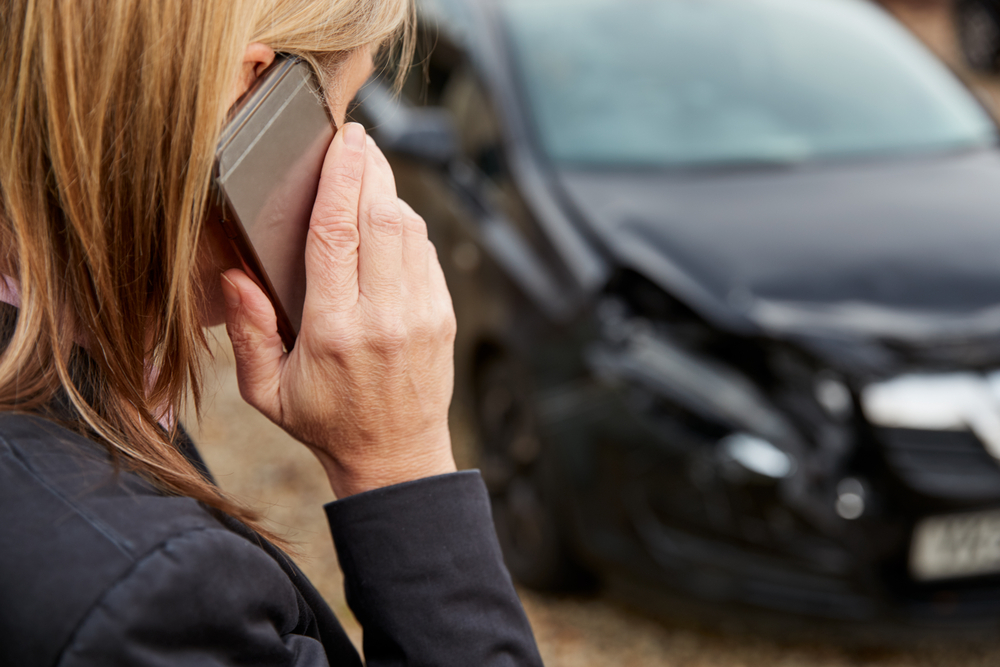 Woman making call on cell phone after uber car accident